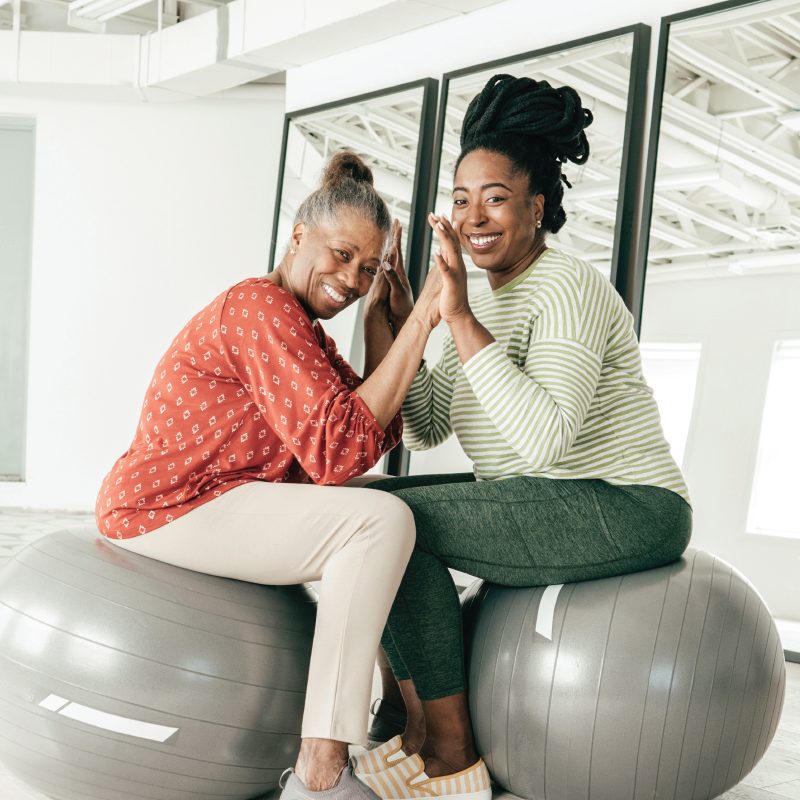 Woman receiving therapy using an exercise ball with a therapist